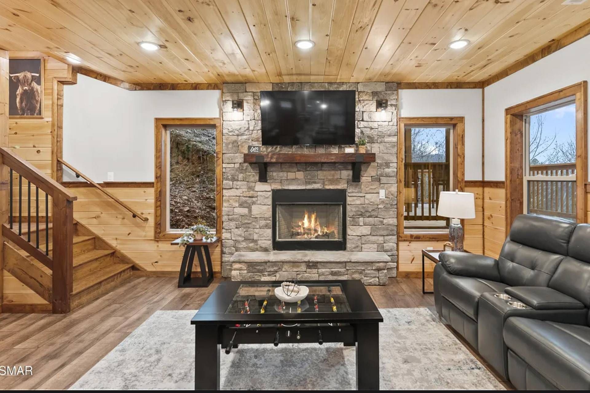 A living room with a stone fireplace, a flat-screen TV, a sofa, and a foosball table.
