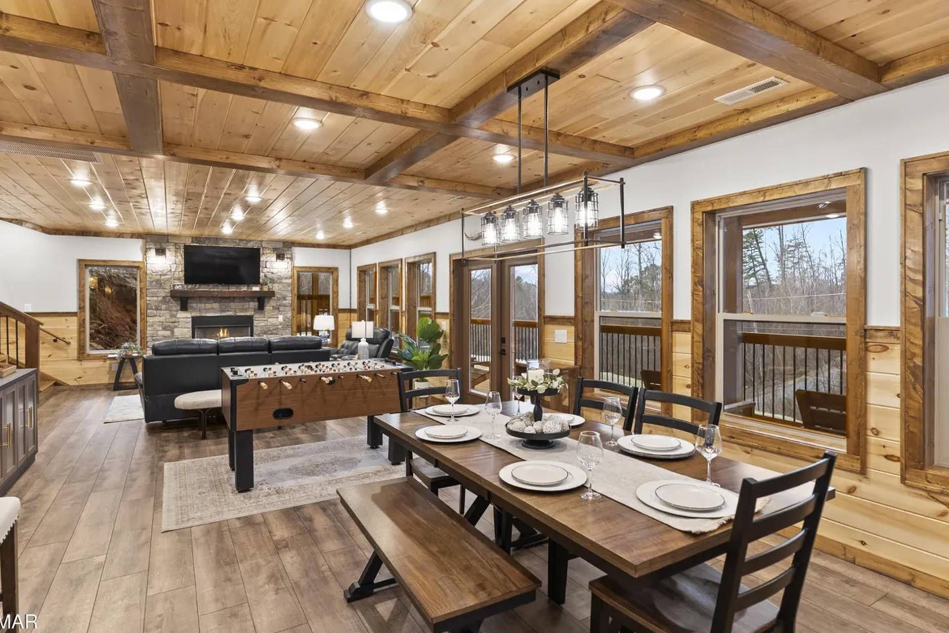 A spacious living area with a fireplace, a foosball table, and a dining area set for six with a wooden table and chairs.