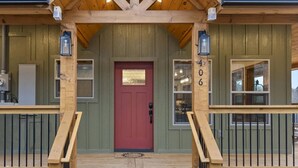 Una baita in legno con una porta rossa, il numero '406' sulla parete e un tappetino d'ingresso con la scritta 'welcome'.