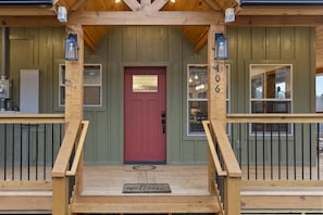 A wooden cabin with a red door, a number '406' on the wall, and a 'welcome' mat at the entrance. - New Cabin Near Gatlinburg & Dollywood (Sevierville)