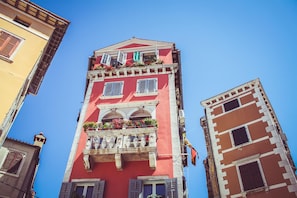 Ein rotes Gebäude mit Balkonen und Fenstern, vor blauem Himmel.
