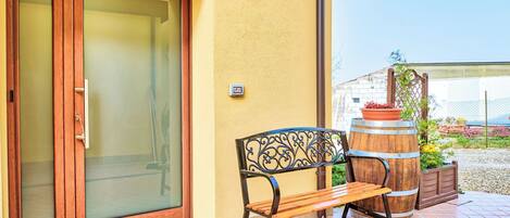A patio with a bench, a wooden barrel, and a door with frosted glass panels.
