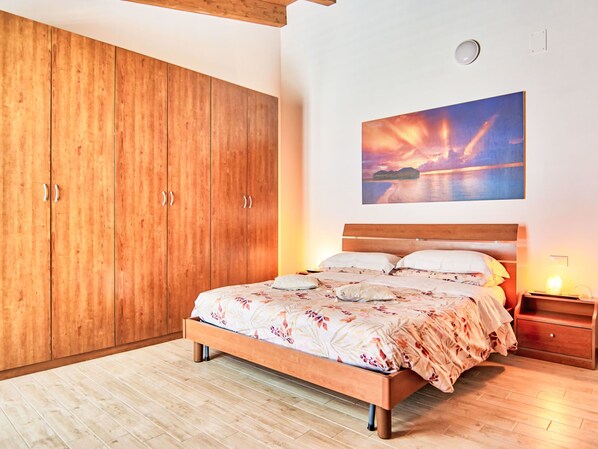 Ein Schlafzimmer mit einem Bett, einem Holzschrank und einem Sonnenuntergangsbild.