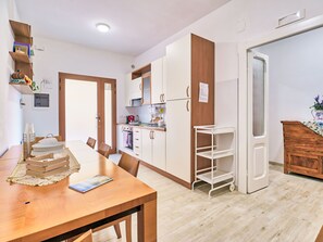Eine moderne Küche mit weißen Schränken, einem Holzespeisetisch und einem weißen Kühlschrank.