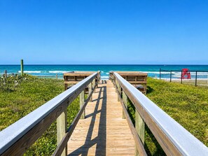 A wooden boardwalk leading to a beach with a lifeguard tower. - Seawoods Beach Retreat - Walk to Beach + Pools (New Smyrna Beach)