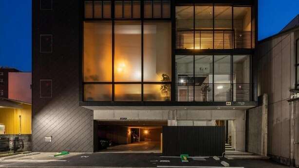 Een modern gebouw met grote ramen, een overdekte ingang en een zichtbare trap.
