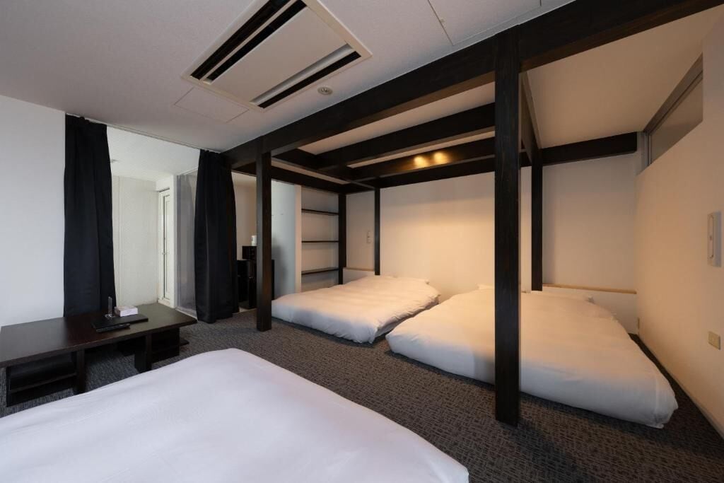 A hotel room with a bunk bed, a desk, and a chair.