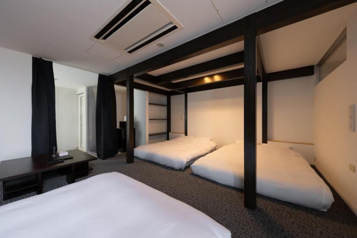 A hotel room with a bunk bed, a desk, and a chair.