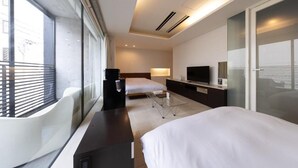 Een moderne hotelkamer met een groot bed, een bureau, een televisie en een balkon met een witte stoel.