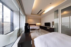 A modern hotel room with a large bed, a desk, a TV, and a balcony with a white chair. - HUNTELIA MATSUYAMA (Matsuyama)