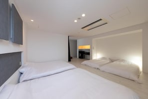 Una habitación de hotel con dos camas, un escritorio y una kitchenette.