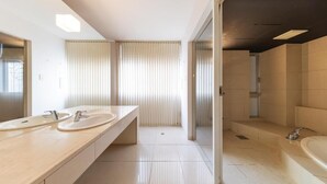 Een moderne badkamer met twee wastafels, een ruime badkuip en een douchehoek.