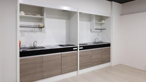 Een moderne keuken met een zwart aanrecht, houten kastjes en witte planken.