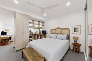 A bedroom with a bed, bedside table, wardrobe, desk, chair, and shelves. - Bright 1-bed Apartment in Neutral Bay (Sydney)