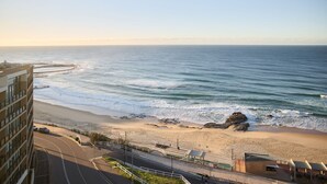 A coastal hotel with a beach view, a road leading to the beach, and a rocky outcrop. - Lumara Holiday Apartment at Newcastle Beach (Newcastle)