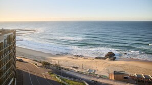 Ein Hotel an der Küste mit Blick auf den Strand, einer Straße, die zum Strand führt, und einem Felsen.