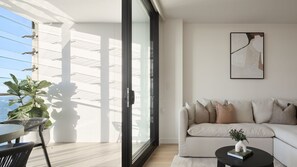 A modern living room with a sofa, a coffee table, and a large window with blinds. - Lumara Holiday Apartment at Newcastle Beach (Newcastle)