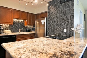 Eine moderne Küche mit Granit Arbeitsplatten, Edelstahlgeräten und einer Ziegelrückwand.