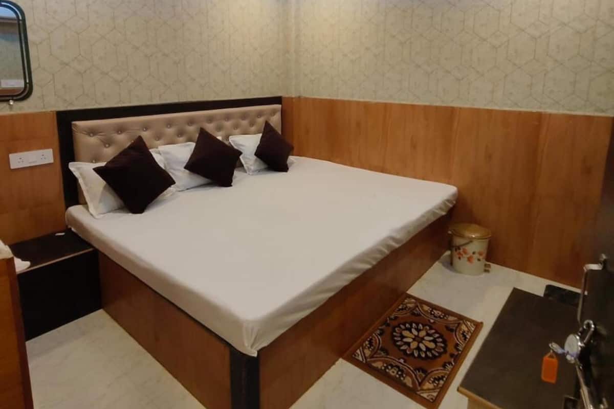 A bedroom with a bed, bedside table, nightstand, and a ceiling with LED lighting.