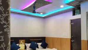 Camera d'albergo con due letti, una ventola a soffitto e illuminazione a LED.