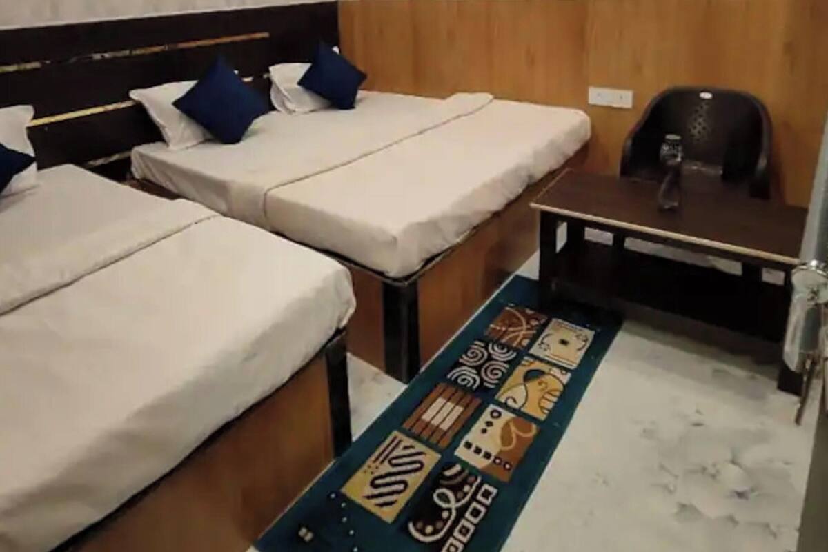 A hotel room with two beds, a desk, a chair, a ceiling fan, and a patterned rug.