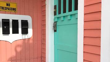 Een huis met een rode gevel, een turquoise deur en een bord met 'NO TRESPASSING'.