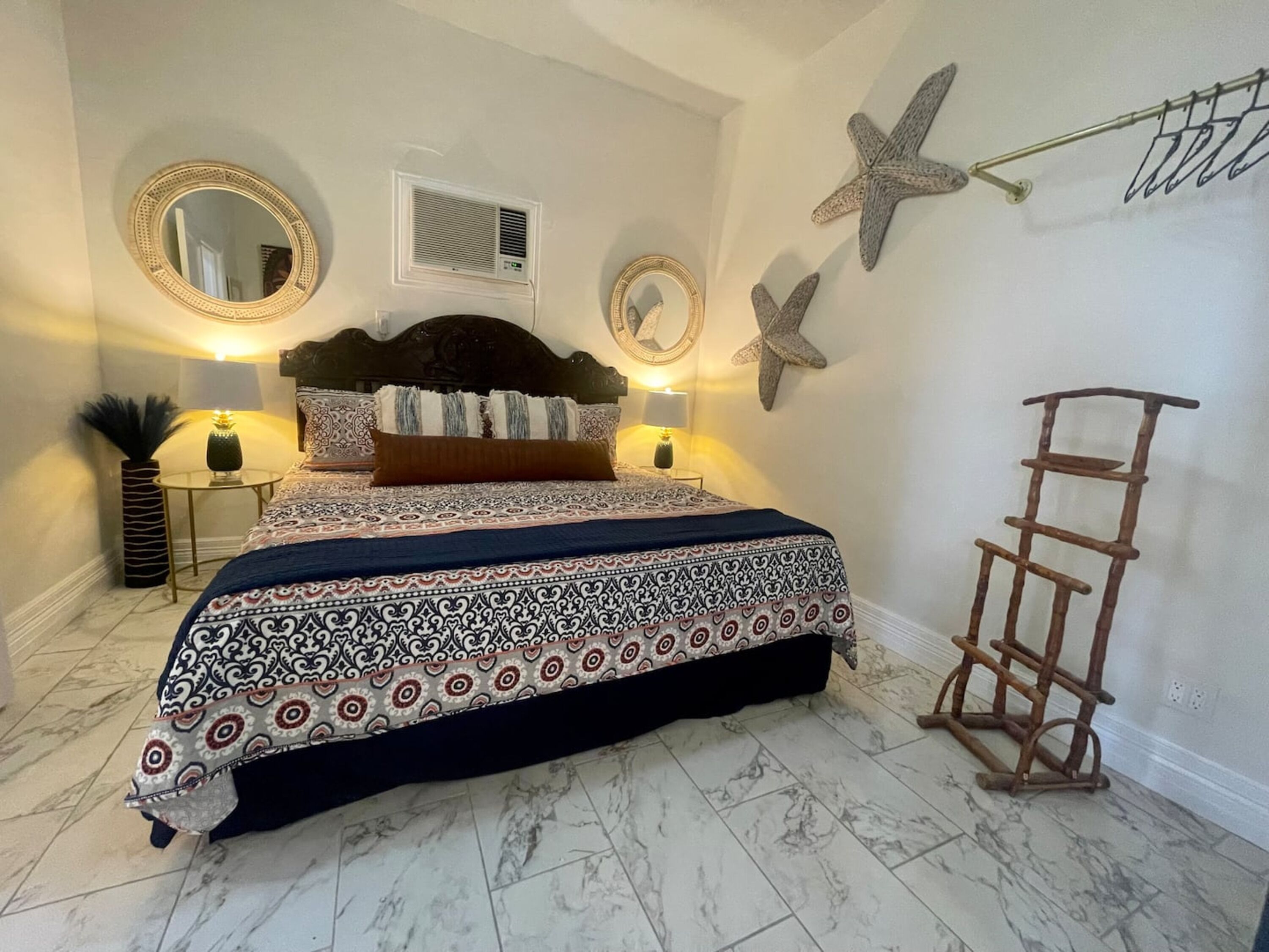 Une chambre à coucher avec un lit, deux tables de chevet, une échelle fixée au mur et des étoiles de mer décoratives.