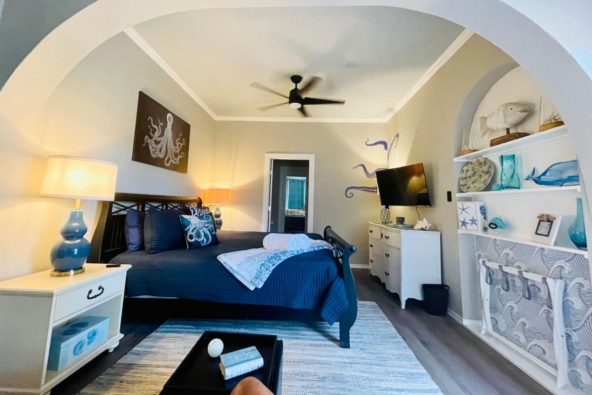 Een slaapkamer met een bed, nachtkastjes, een televisie en een dressoir.