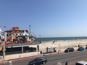 A coastal building with a carousel, a beach in the background, and a road with cars. - Stylish Condos in Galveston (Galveston)