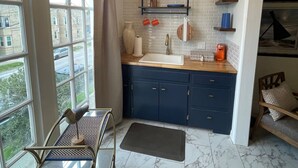 Una cocina moderna con un ventanal grande, un comedor con mesa y sillas, y vistas a la calle.