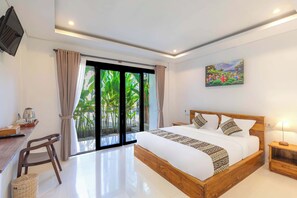 Une chambre d’hôtel avec un grand lit, un bureau avec une bouilloire, une chaise, une télévision et un tableau au mur.