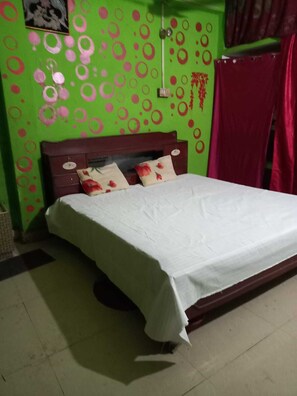 Ein Bett mit weißer Bettdecke, einem Holz-Kopfteil und zwei Kissen mit Blumenmuster.