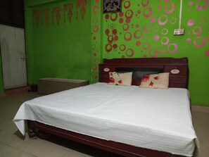 Ein Schlafzimmer mit Bett, Kissen, einem Holz-Kopfteil und einer grünen Wand mit kreisförmigen Mustern.