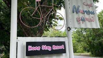 A signboard with a bicycle, a sign for Hone Stay Resort, and contact numbers.