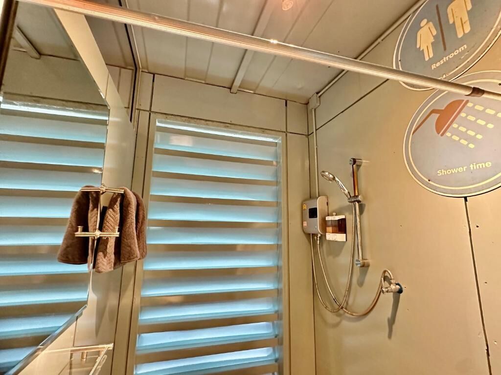 A bathroom with a shower, a towel rack, and a sign indicating a restroom and shower time.