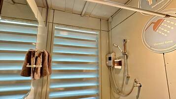 A bathroom with a shower, a towel rack, and a sign indicating a restroom and shower time.