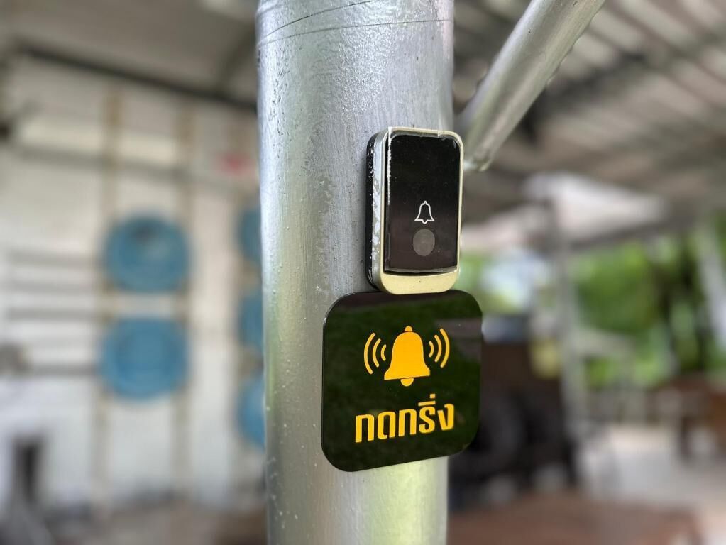 Um poste de metal com um botão de sino de emergência preto e amarelo e um smartphone com um ícone de sino.