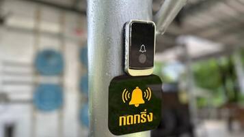 Um poste de metal com um botão de sino de emergência preto e amarelo e um smartphone com um ícone de sino.