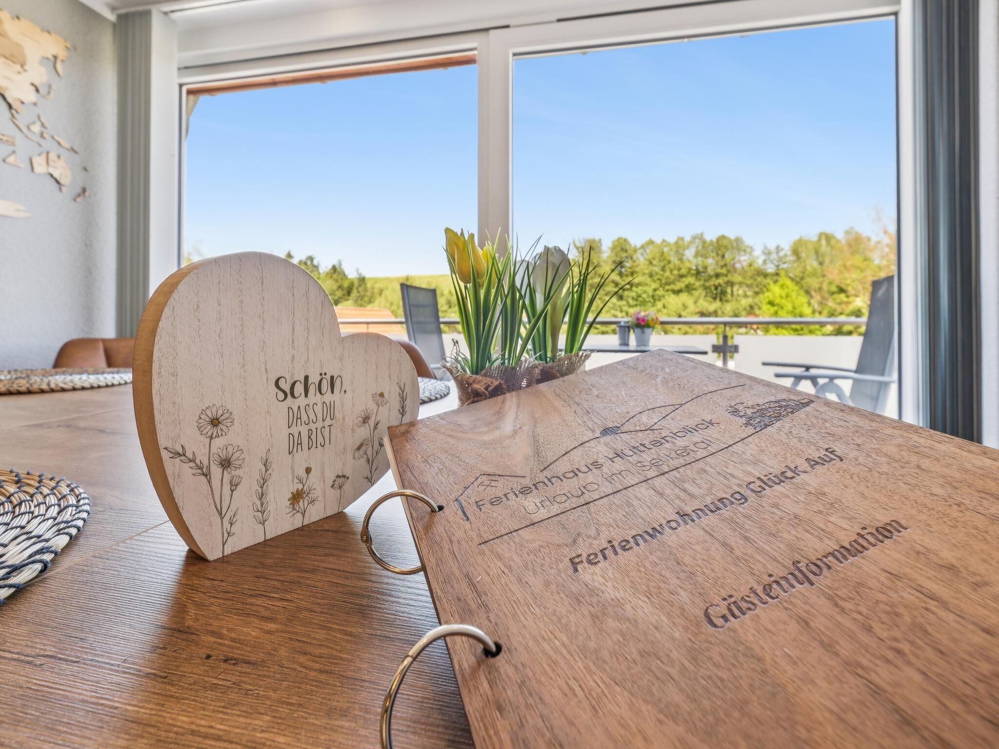 A wooden table with engraved text and a heart-shaped object with floral designs.