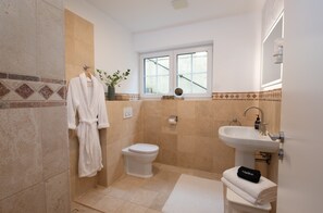 A bathroom with a toilet, sink, and a robe hanging on the wall.