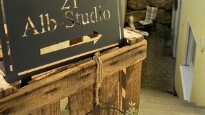 Un letrero de madera con '21 Alb-Studio' y una flecha que apunta a la derecha, montado sobre un poste de madera rústico.