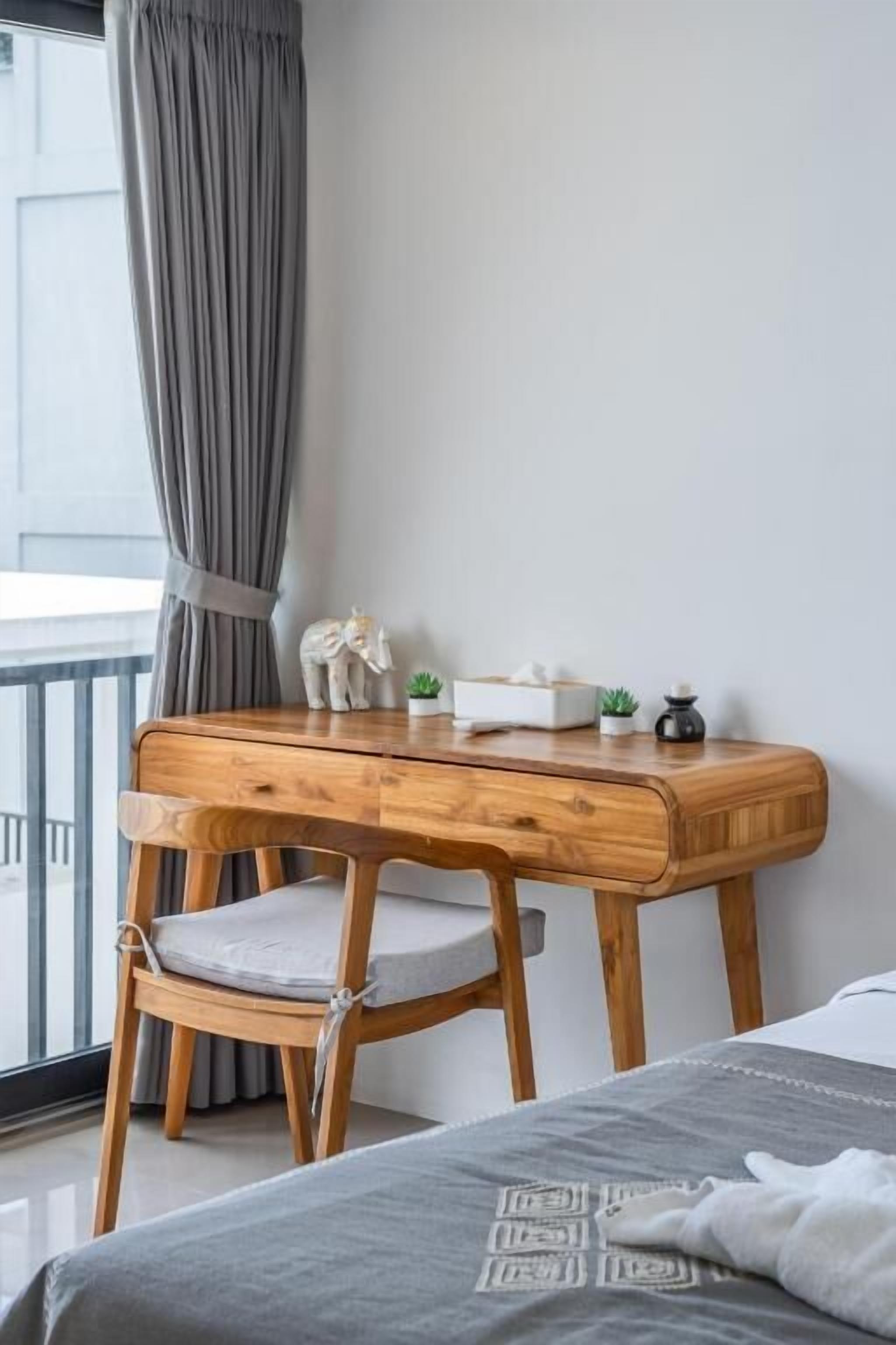 Een houten bureau met een stoel, een kleine plant en een decoratief object op het bureau.