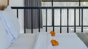 A hotel room with a large window, a balcony, and a bed with white linens and orange flowers. - Wolu 1BR Canggu Pool Villa Parking Wifi (Bali)