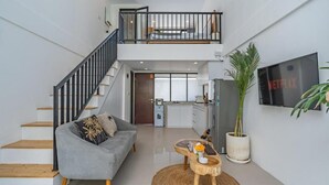 A modern interior with a staircase, grey sofa, wooden coffee table, and a large potted plant. - Wolu 1BR Canggu Pool Villa Parking Wifi (Bali)