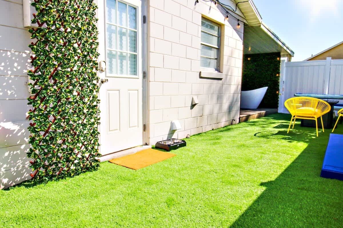 A house with a white exterior, a green lawn, and a yellow chair.