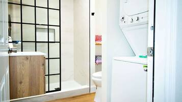 A bathroom with a shower enclosure, a toilet, and a washing machine.