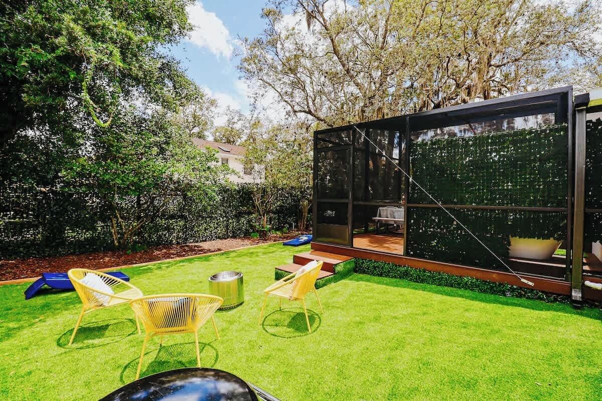 Eine moderne Außenpatio mit Glasveranda, Rasen und Gartenmöbeln.