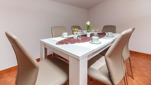 A dining area with a white table, beige chairs, and a decorative leaf placemat. - Kristalis by Interhome (Medulin)
