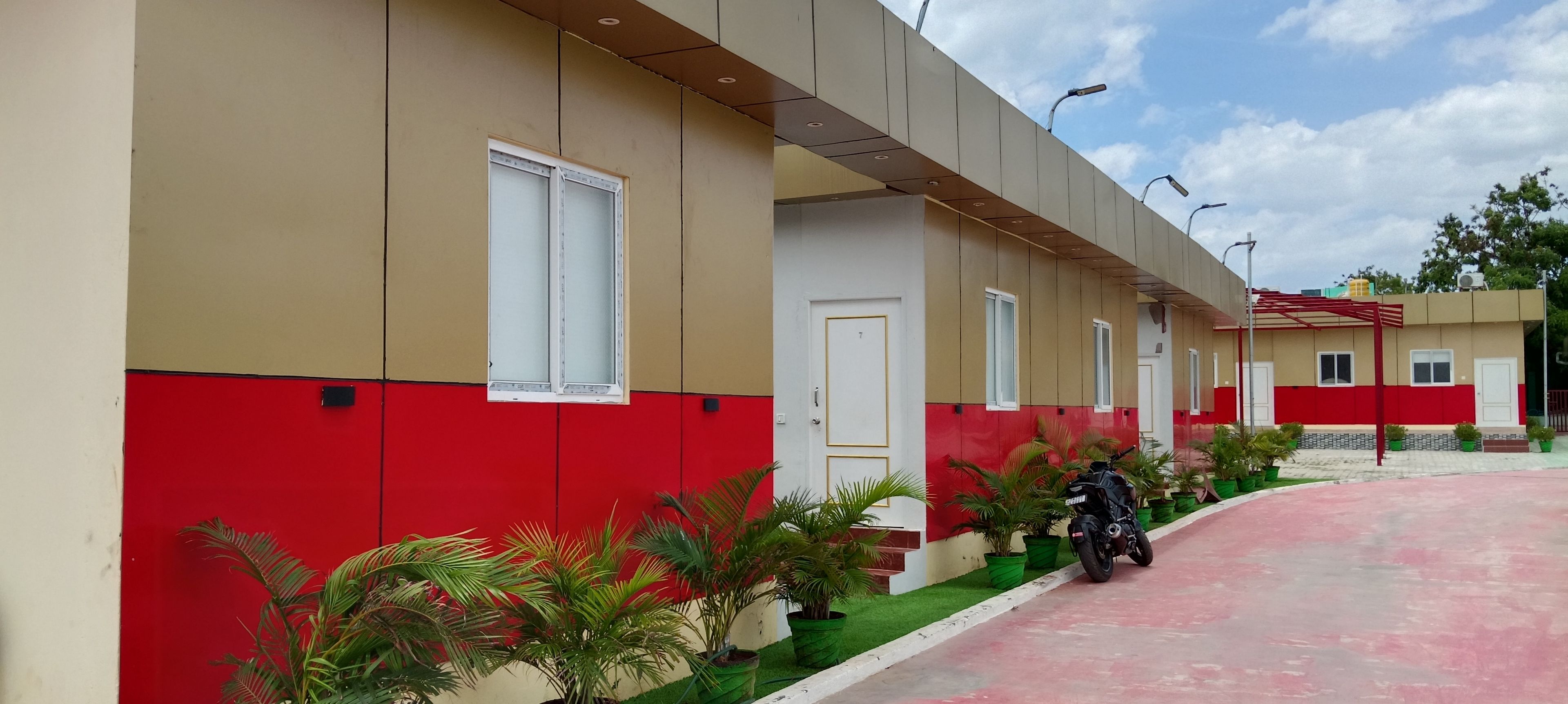 A building with a red and beige facade, a motorcycle parked in front, and a clear sky.