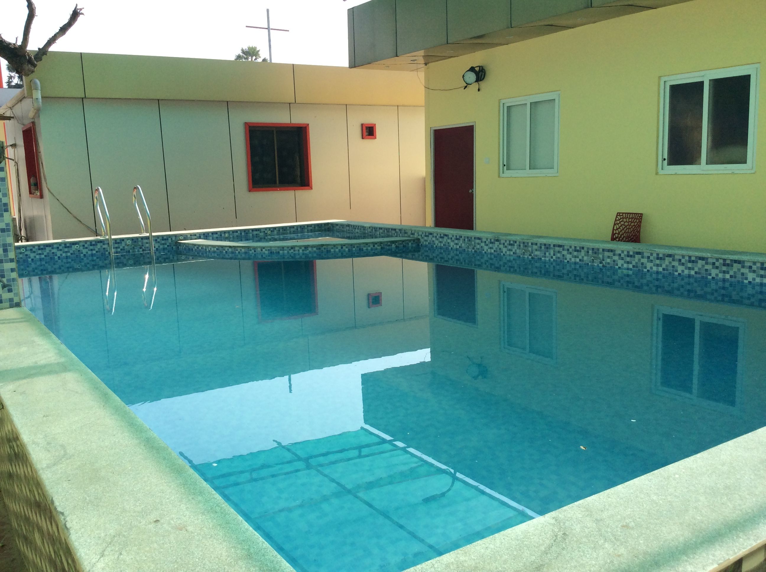 A swimming pool with clear water, surrounded by a tiled deck.